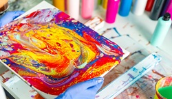 Painted canvas with paints in background
